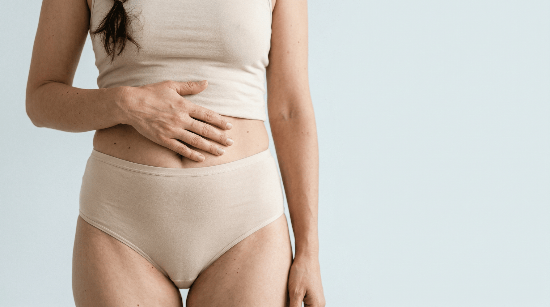 Vrouw met hand op buik toont comfort en selfcare. iYone voor natuurlijke intieme verzorging en bewustzijn