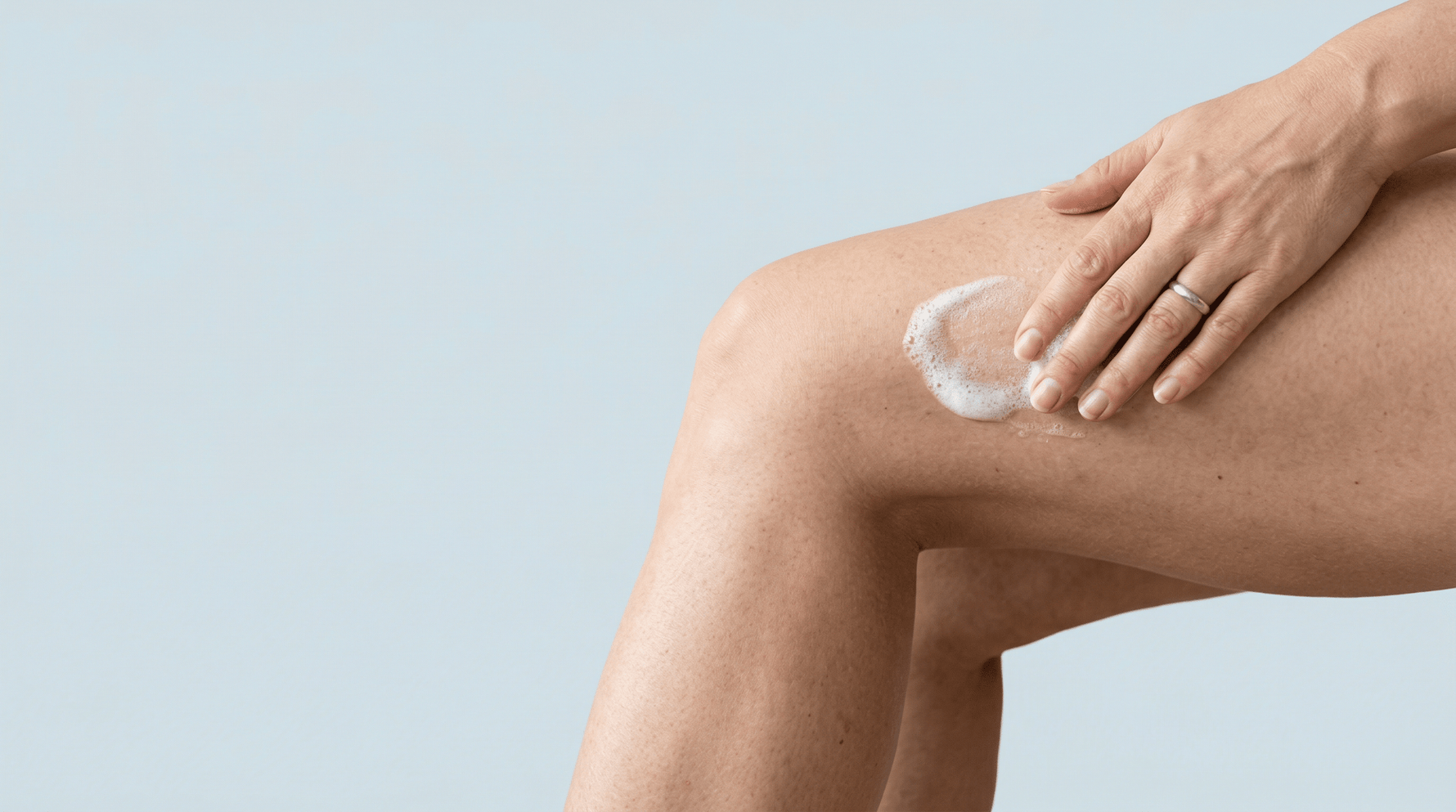 Hand brengt Yoni Foam, iYone's milde reinigingsfoam, aan op de huid voor verzorging en selfcare