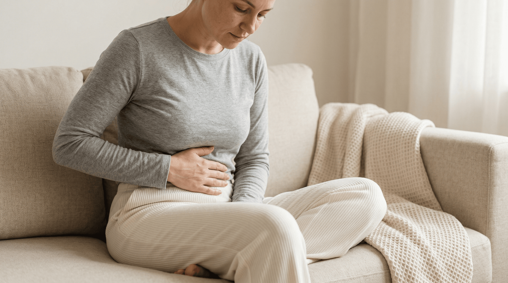 Vrouw met menstruatiepijn zoekt ontspanning en intiem comfort thuis op de bank met Yoni selfcare